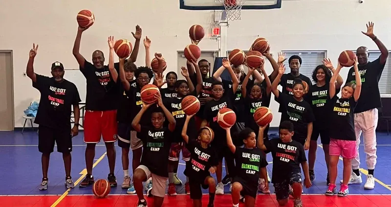 Young athletes at a basketball camp raise their balls